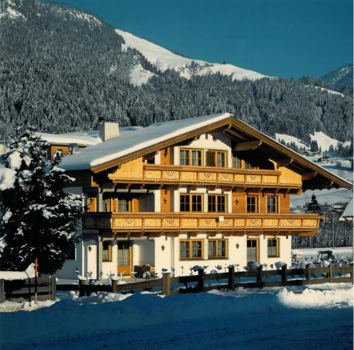 a large wooden house with snow on the ground at Apartment Daxauer in Sankt Johann in Tirol