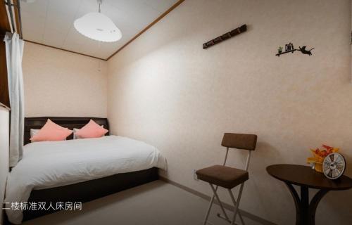 Un dormitorio con una cama con almohadas rosas y una mesa. en 10mins train to Namba, 4 mins walk to stn, 2 floors japanese style , 2-8 people, en Osaka