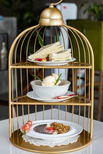 a gold bird cage with plates of food in it at Tisha Langkawi Wellness Resort in Pantai Cenang