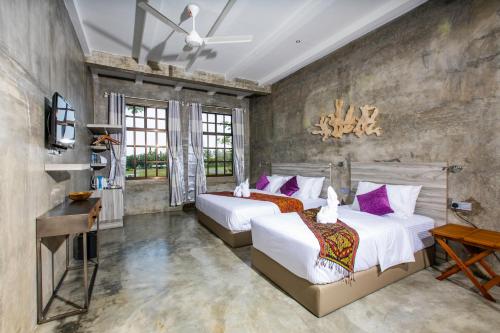 Tisha Langkawi Wellness Resort في بانتايْ سينانج: سريرين في غرفة بها نافذتين