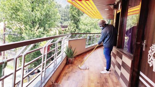a man with a mop standing on a balcony at Cloud 7 in Nainital