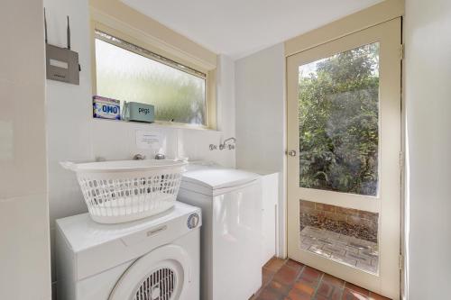 a laundry room with a washing machine and a window at Bungunyah Apartments in Croydon