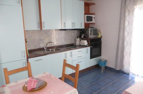 une cuisine avec des armoires blanches, une table et un évier dans l'établissement Castillete 5 by El Sirocco, à Puerto de Mogán