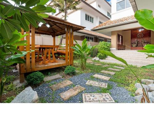 a wooden gazebo with a wooden table in a garden at Angel Pool Villa Phuket - SHA Extra Plus in Phuket Town