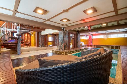 an indoor swimming pool with a wicker chair in a house at Angel Pool Villa Phuket - SHA Extra Plus in Phuket Town