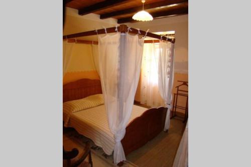 Schlafzimmer mit einem Bett mit Baldachin und Vorhängen in der Unterkunft Cazabonne in Salles