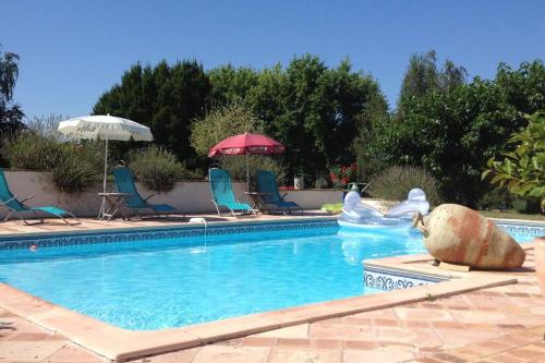 une piscine avec chaises et parasols dans l'établissement Cazabonne, à Salles