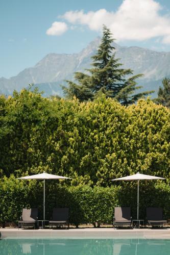 two chairs and umbrellas next to a swimming pool at Hotel Pollinger in Merano