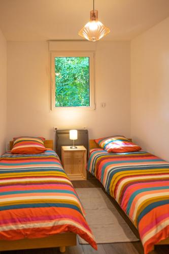 deux lits jumeaux dans une chambre avec fenêtre dans l'établissement le chalet, à Airaines