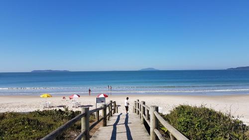 a man walking down a wooden path to the beach at Pousada Pedra da Gaivota in Bombinhas