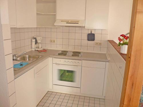a small kitchen with white cabinets and a sink at Haus Seeschwalbe Ferienwohnungen in Göhren