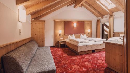 a hotel room with two beds and a couch at Hotel Auhof Kappl in Kappl