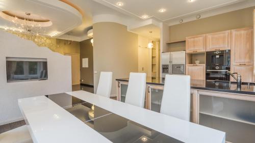 a kitchen with a glass table and white chairs at Grand Lehe Beach Apartment in Pärnu