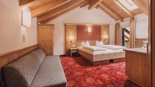 a hotel room with two beds and a couch at Hotel Auhof Kappl in Kappl