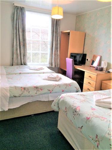 a bedroom with two beds and a desk and a window at Luther King House in Manchester