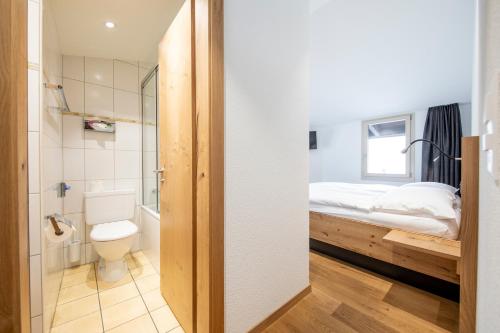 a small bathroom with a bed and a toilet at Hotel Meiringen in Meiringen