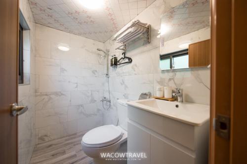 a white bathroom with a toilet and a sink at Lala Easystay in Xiaoliuqiu