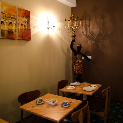 two tables in a restaurant with a statue on the wall at Hôtel Héliot, Cosy Places by Charme & Caractère in Toulouse