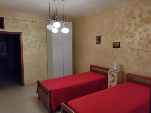 two beds in a room with red sheets at Casa Vacanza Villa Teresa - Appartamento Girasole in Torre Lapillo