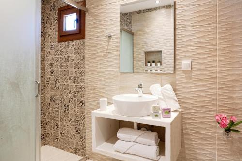 ein Badezimmer mit einem weißen Waschbecken und einem Spiegel in der Unterkunft Stenaki in Skiathos-Stadt