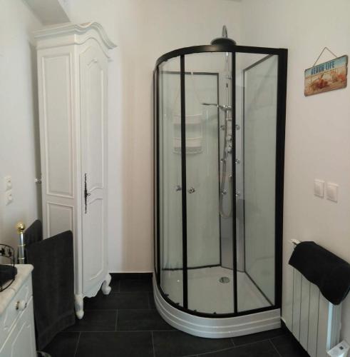 La salle de bains est pourvue d'une douche en verre et de carrelage noir. dans l'établissement Le Rumain, à Hengoat