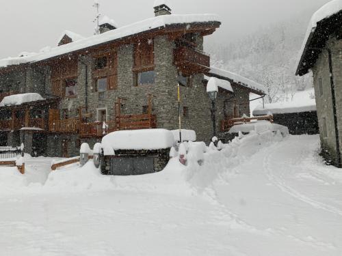a house covered in snow in front at Bilocale pietra e legno immerso nella natura in Morgex