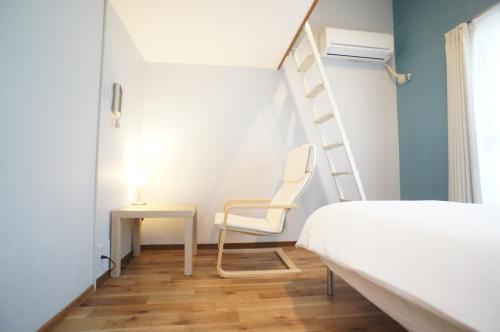 a bedroom with a ladder next to a bed and a desk at Plusone Nishikoen in Fukuoka