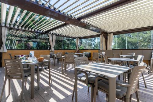 un restaurante con mesas, sillas y ventanas en Hôtel Corniche du Liouquet, en La Ciotat