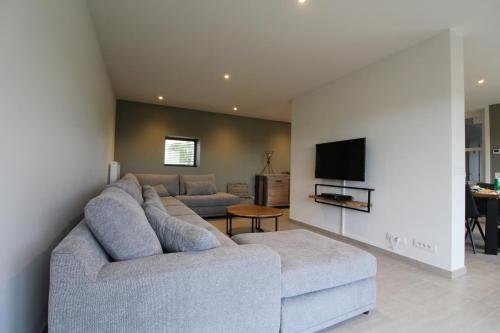 a living room with a couch and a tv at De Ast by De Oude Kaasmakerij in Passendale
