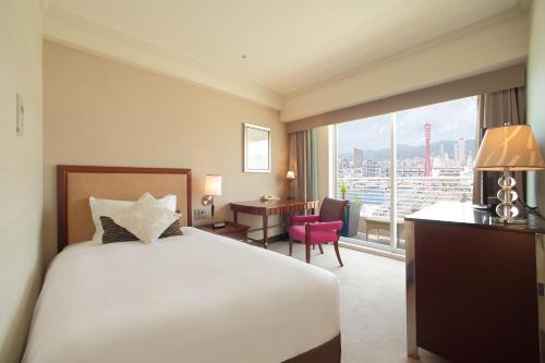 a hotel room with a bed and a desk and a window at Kobe Meriken Park Oriental Hotel in Kobe