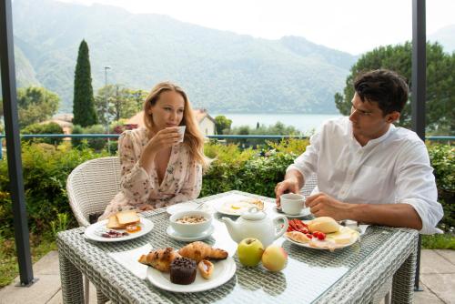 a man and a woman sitting at a table with food at Park Hotel Abbadia in Abbadia Lariana