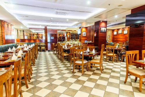 een restaurant met houten tafels en stoelen en een geruite vloer bij Hotel Ascent Biz in Noida