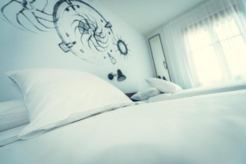 a bedroom with a white bed with a clock on the wall at Hotel Bernina Geneva in Geneva