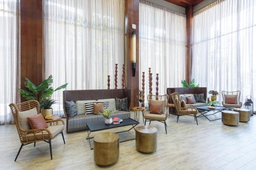 a living room with chairs and a couch and tables at The Gems Mining Pool Villas Pattaya in Nong Prue
