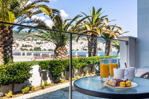 a table with a plate of food and drinks on a balcony at Olia Green Residence in Skopelos Town