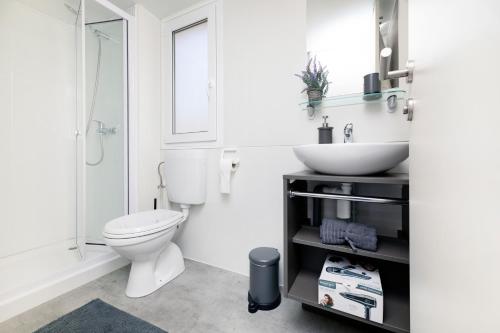 a white bathroom with a toilet and a sink at Veda Mobile Home in Baška Voda