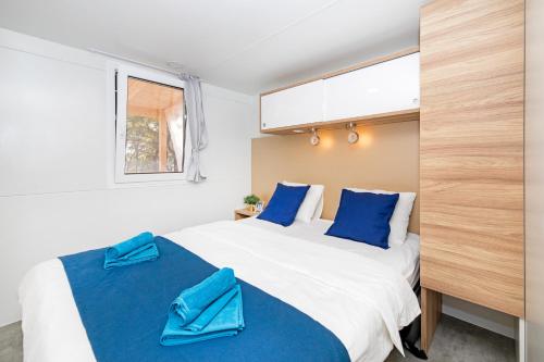 a bedroom with a large bed with blue pillows at Veda Mobile Home in Baška Voda