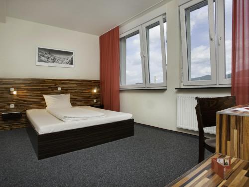 a bedroom with a bed and two windows at hotelo Heidelberg in Heidelberg