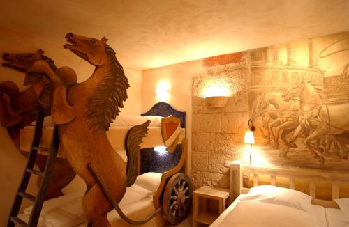 ルストにある4-Sterne Superior Erlebnishotel Colosseo, Europa-Park Freizeitpark & Erlebnis-Resortの木製の馬の壁画が壁に施されたベッドルーム