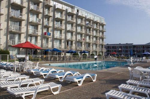 a hotel with a row of lounge chairs next to a pool at Acropolis Oceanfront Resort in North Wildwood