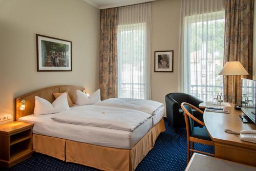 アイゼナハにあるグロッケンホフのベッドとデスクが備わるホテルルームです。
