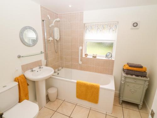 a bathroom with a tub and a sink and a toilet at Garnedd in Holyhead
