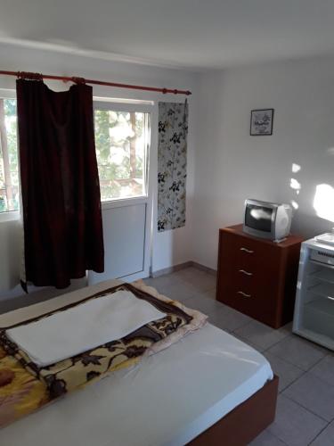 a bedroom with a bed and a microwave and a window at vila catrini in Costinesti