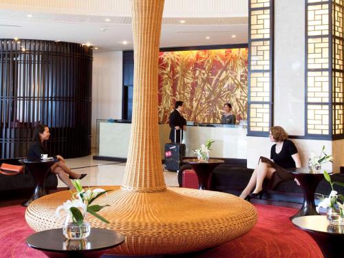 Novotel Ha Long Bay Hotel في ها لونغ: عمود كبير في اللوبي فيه ناس جالسين على الطاولات