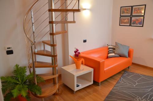 a living room with an orange couch and a spiral staircase at Il Vicolo in Como