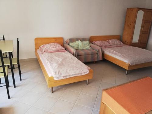 Habitación con 2 camas y una silla. en Mama Meri en Balchik