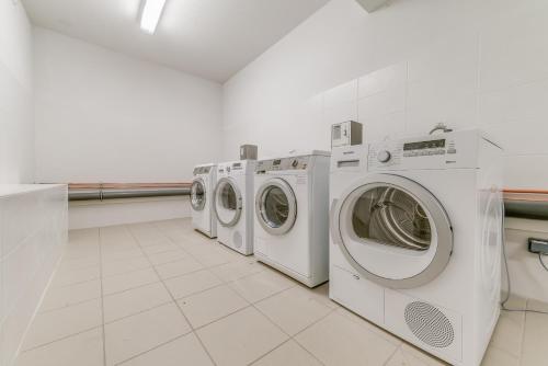 une rangée de machines à laver dans une buanderie dans l'établissement Residence Le Roc Noir by Alpapart, à La Rosière