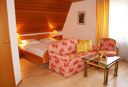 a hotel room with a bed and a couch and a chair at Pension Rose in Bretzfeld
