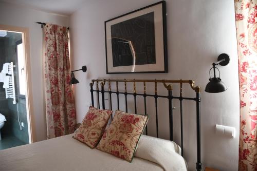 a bed with two pillows and a picture on the wall at La Tronera del Bierzo Restaurante-Hotel in Villadepalos