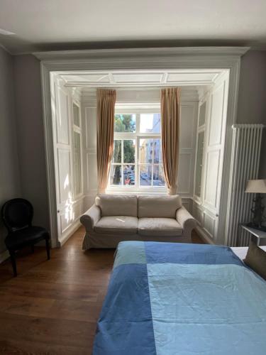 a bedroom with a couch and a large window at Das Nikolai Hotel in Munich